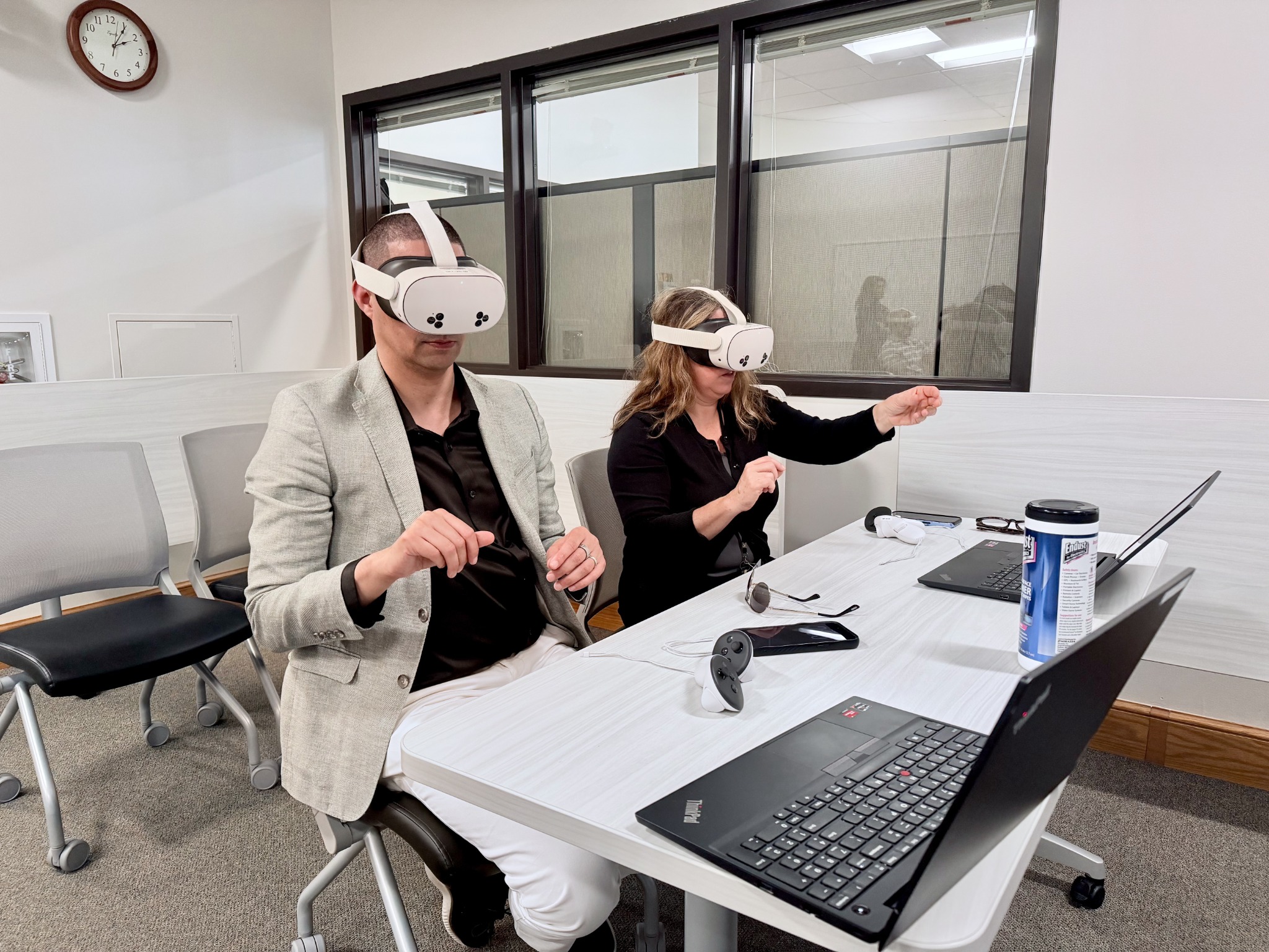 Two participants seated at a table trying VR headsets