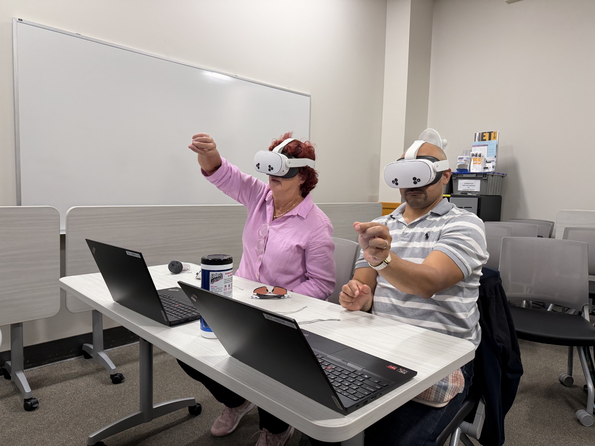Two workshop participants exploring VR headsets with hand gestures